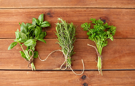 绿色,香料或草药的成群的欧芹,罗勒迷迭香木板上木板上的绿色香料或草药图片