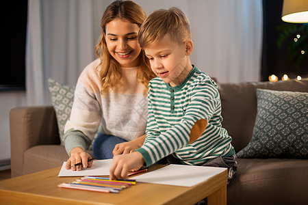 家庭休闲人的母亲小儿子用彩色铅笔纸家里画画母亲儿子家用铅笔画画图片