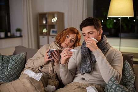健康,流感人们的生病的年轻夫妇戴着围巾,用温度计测量温度,家喝热茶生病的夫妇带着温度计茶家图片