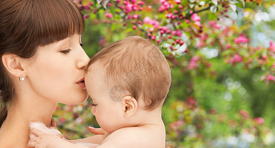 家庭母亲的亲密的快乐年轻母亲亲吻小婴儿自然春天樱花背景靠近快乐的母亲亲吻孩子花园里图片