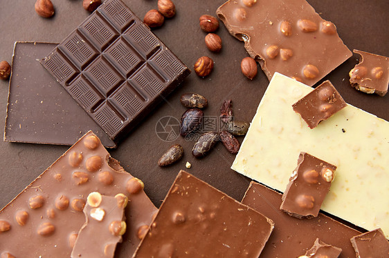 糖果,糖果食品牛奶,深色白色巧克力棒与榛子可可豆的棕色背景巧克力棒与榛子可可豆图片