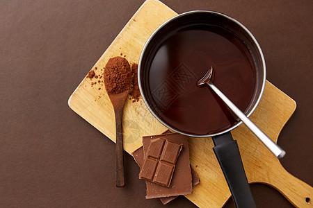 糖果,糖果烹饪锅与融化的热巧克力,可可粉勺子木板棕色背景锅里有融化的热巧克力可可粉图片