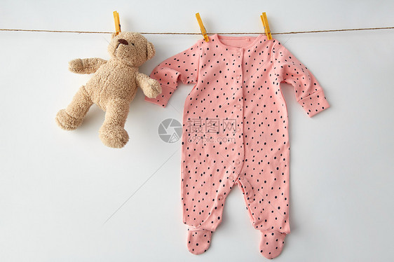 衣服,洗衣,婴儿期服装粉红色长袖西装为女婴与点打印挂晾衣绳与泰迪熊别针白色背景小女孩用泰迪挂绳子上的紧身衣图片
