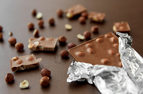 糖果,糖果食品牛奶巧克力棒与榛子箔包装棕色背景牛奶巧克力棒与榛子箔纸包装图片