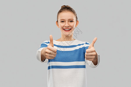 手势人的微笑的十几岁女孩套衫上拇指灰色背景微笑的十几岁大拇指图片