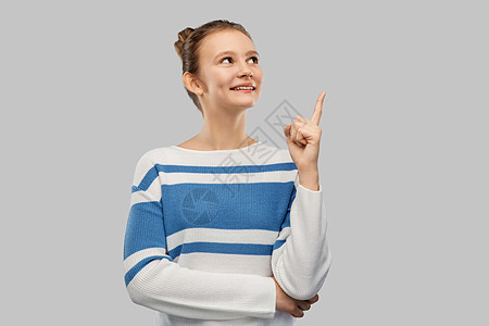 想法人的微笑的十几岁女孩套衫上指着灰色的背景穿着套衫的快乐少女指着手指图片
