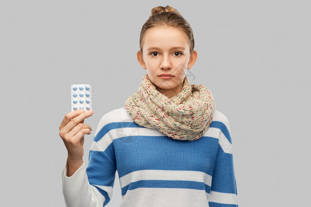 健康,医学人的生病的十几岁女孩戴着围巾,带着灰色背景的药丸带着药的围巾的生病的十几岁女孩图片