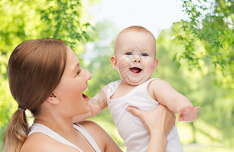 家庭母亲的快乐的微笑年轻母亲与小婴儿超过绿色的自然背景母亲带着孩子绿色的自然背景下图片