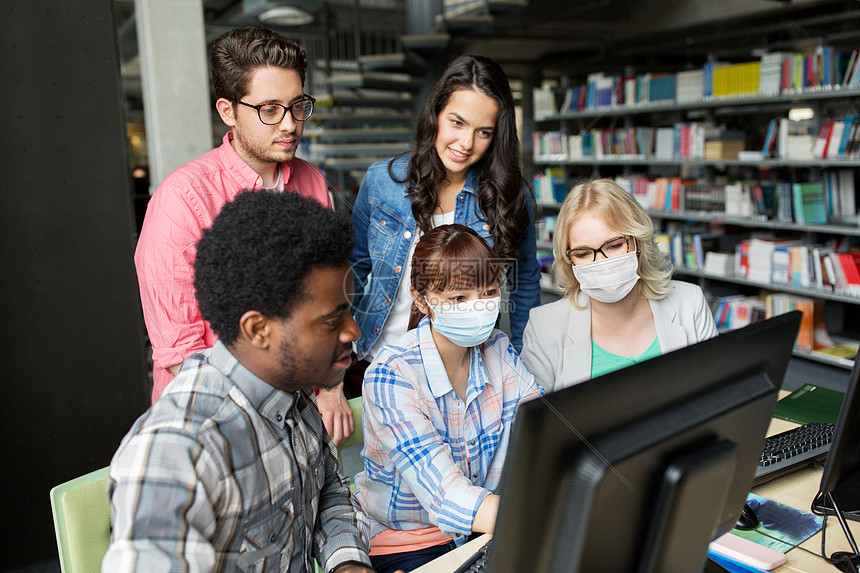 健康教育大流行群快乐微笑的国际学生戴着保护医学面具,学校图书馆用电脑保护免受病感染学生戴着医用口罩,图书图片