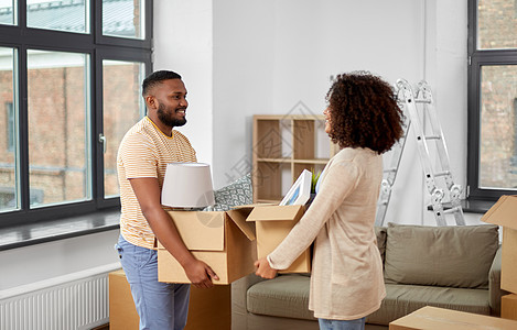 移动,维修房地产快乐的非裔美国人夫妇新家的纸板箱里装东西幸福的夫妇带着箱子搬到新家图片