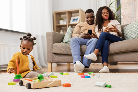童年人的小非洲裔美国女婴玩玩具块父母用智能手机家非洲女婴家玩玩具积木图片