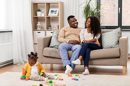 家庭,父母人的快乐的非裔美国人母亲父亲看着婴儿女儿家里玩玩具块非洲家庭带着宝贝女儿家玩图片