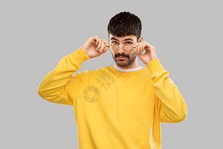 视觉人的戴眼镜的年轻人灰色背景的黄色运动衫戴眼镜黄色运动衫的年轻人图片