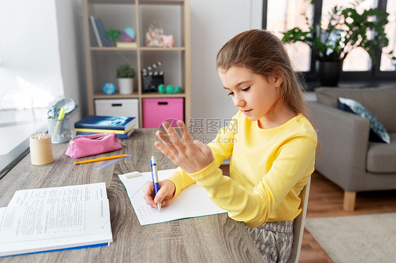 孩子,教育学的快乐的学生女孩,用书本数手指,家里写笔记本学生女孩带着书家里写笔记本图片