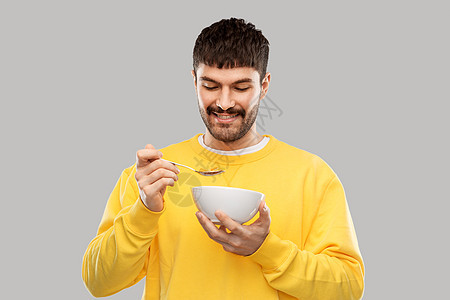 食物人的快乐微笑的年轻人吃灰色背景的谷物快乐微笑的年轻人吃谷物图片