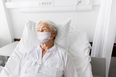 医学,健康安全大流行老年妇女病人躺床上,戴着面部防护医疗面罩,以防止医院病房的病疾病老妇病人戴着面具躺医院的床图片