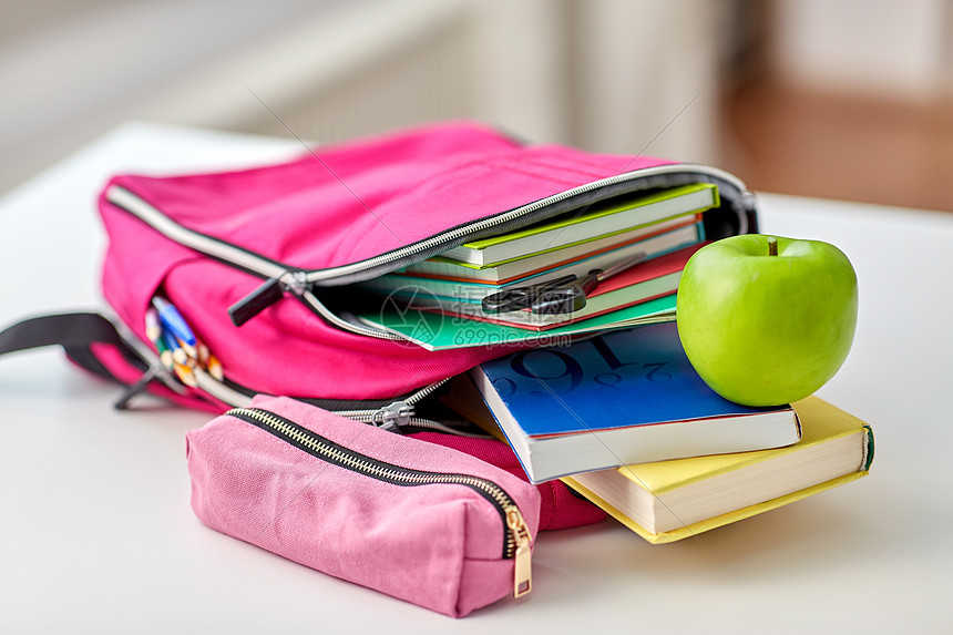 教育学粉红色背包与书籍学用品,绿色苹果家里的桌子上桌上的背包苹果学用品图片