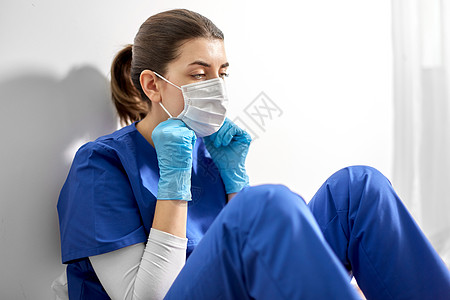 医学,医疗保健大流行悲伤的年轻女医生或护士戴着面罩,以防止病疾病坐医院的地板上戴防护面罩的悲伤医生或护士图片