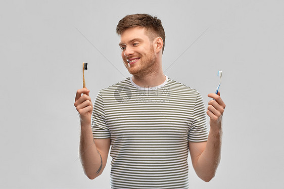 牙科护理,口腔卫生人们的快乐的微笑年轻人比较木制塑料牙刷灰色背景男人比较木制塑料牙刷图片