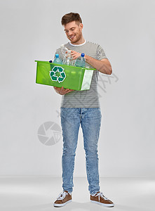 回收,废物分类可持续微笑的年轻人穿着条纹T恤持有盒与塑料瓶灰色背景微笑的年轻人分类塑料废物图片