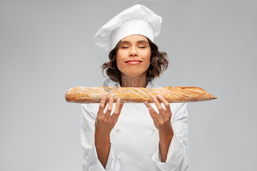 ‘~烹饪,烹饪面包店的快乐微笑的女厨师或面包师托克持有法国面包或面包灰色背景快乐的女厨师与法国面包或面包  ~’ 的图片