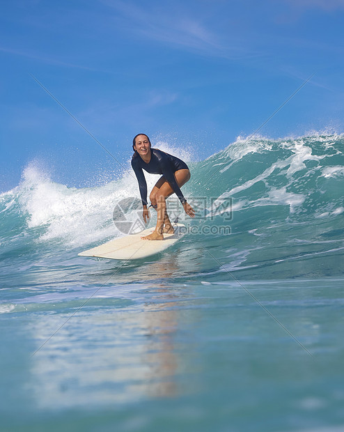 阳光明媚的日子里,女冲浪者蓝色的波浪上冲浪图片