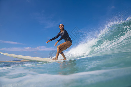 阳光明媚的日子里,女冲浪者蓝色的波浪上冲浪图片