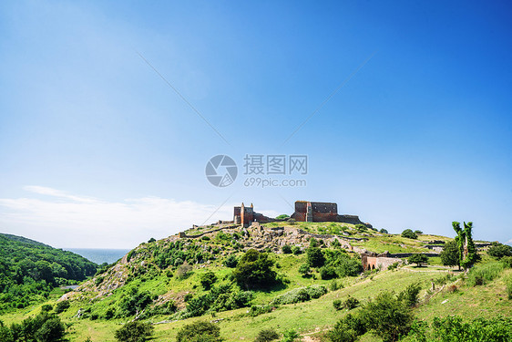 蓝天下的夏天,绿山顶上的城堡被毁了图片