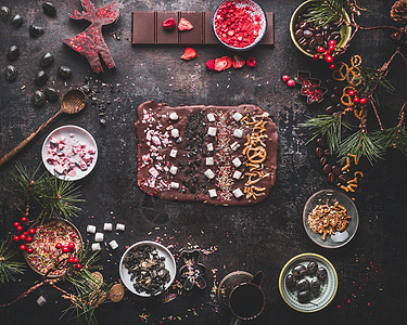 美味的圣诞巧克力树皮与焦糖,棉花糖,坚果糖果圣诞甜蜜礼物准备与配料黑暗背景与上面的风景图片