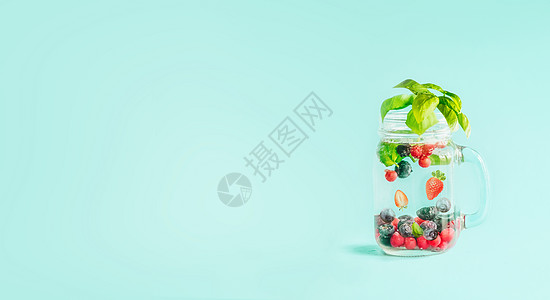 浆果解水果注入水梅森罐,与叶子桌子上的阳光绿松石蓝色背景夏季情绪饮料生活方式健康的背景图片
