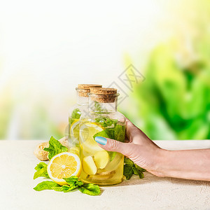 女手瓶姜,柠檬,薄荷柠檬水白色桌子上的绿色自然背景健康的夏季饮料天然免疫助推器注入水果水图片