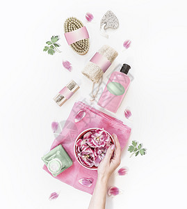 女手着水碗,白色桌面上有粉红色的花,有各种环保的水疗中心护肤工具化妆品瓶上面的风景现代天然化妆品零浪费图片