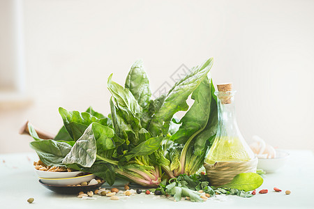 新鲜的有机菠菜带橄榄油瓶放厨房的桌子上,背景很轻健康的烹饪理念图片