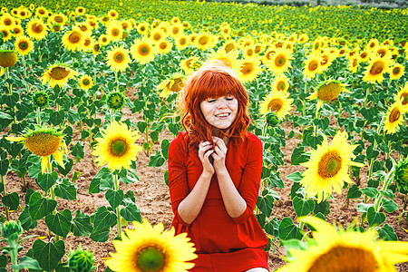 可爱的红头发女人向日葵的田野里享受这天背景