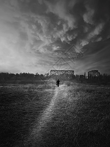 场景拍摄黑白的场景,垂直拍摄的流浪者男子剪影走窄的道路扔荒野寂静的夜晚气氛,戏剧的景观,孤独孤独的背景