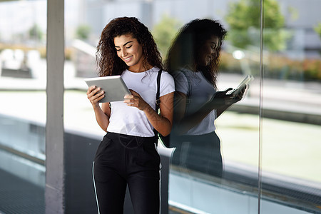 快乐的年轻阿拉伯妇女商业背景中用数字平板电脑穿着运动服的快乐女孩图片