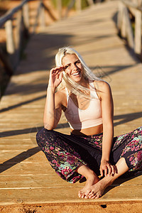 西牙安达卢西亚的卡迪兹美丽的海滩上享受日落的女人年轻的女微笑着坐木桥上微笑的女人美丽的海滩上享受日落图片