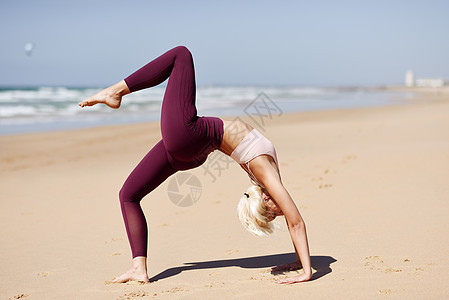 高加索女人海滨练瑜伽年轻的女站桥上的姿势海滩卡迪兹,安达卢西亚,西牙高加索金发女人海滩上练瑜伽图片