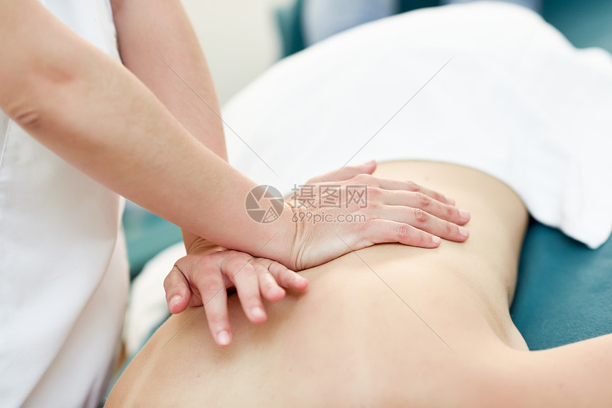 年轻女子接受专业治疗师的背部按摩女病人正水疗中心接受治疗年轻女子接受专业治疗师的背部按摩图片