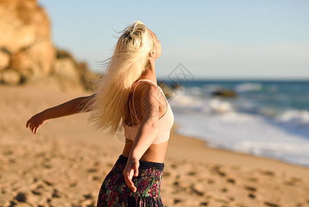 西牙安达卢西亚的卡迪兹美丽的海滩上享受日落的女人年轻的女张开双臂呼吸大海的空气女人美丽的海滩上享受日落背景图片