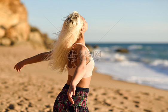 西牙安达卢西亚的卡迪兹美丽的海滩上享受日落的女人年轻的女张开双臂呼吸大海的空气女人美丽的海滩上享受日落图片