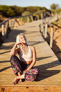 西牙安达卢西亚的卡迪兹美丽的海滩上享受日落的女人年轻的女微笑着坐木桥上微笑的女人美丽的海滩上享受日落图片