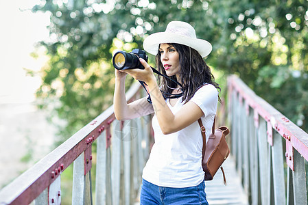 美丽的徒步旅行者年轻女人用无镜相机拍照,戴着草帽,乡下徒步旅行徒步旅行者女人用无镜相机拍照图片