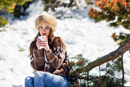 美女 饮酒穿着冬天衣服的女喝热咖啡年轻的女人冬天享受雪山,内华达山脉,格拉纳达,西牙年轻的女人冬天享受雪山背景