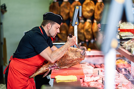 男屠夫家现代肉店里烤火腿屠夫家现代化的肉店里烤火腿图片