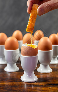 人蘸吐司士兵个煮鸡蛋的鸡蛋白蛋杯个木桌上图片