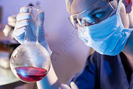女科学家医学或科学研究员或医生实验室里看着瓶红色的溶液,实验室的设备她身后失去了焦点图片