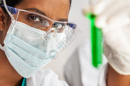 印度女亚洲女科学家或医生医学研究实验室或实验室中观察绿色溶液的试管图片