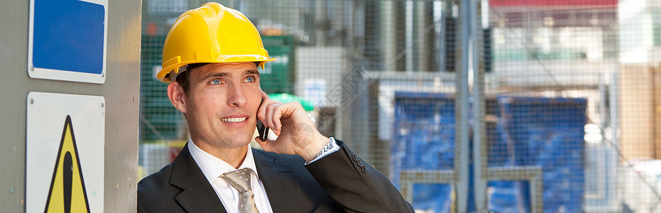男子男建筑工头建筑工人工地经理工程师或测量员建筑工地戴安全帽手机上交谈的全景全景图片