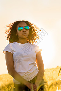 美丽的混合种族,混血的非裔美国女女孩,十几岁的年轻女人,戴着太阳镜,日落或日出的小麦,玉米或大麦图片
